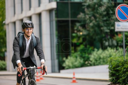 Foto de Empresario en bicicleta. Joven en traje negro montando una bicicleta - Imagen libre de derechos