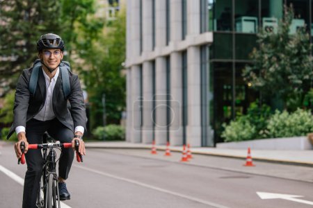 Téléchargez les photos : Un homme d'affaires à vélo. Jeune homme en costume noir en vélo - en image libre de droit
