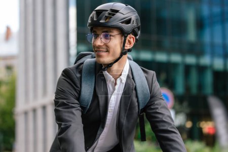 Téléchargez les photos : Un homme d'affaires à vélo. Souriant jeune homme d'affaires en helet à vélo - en image libre de droit