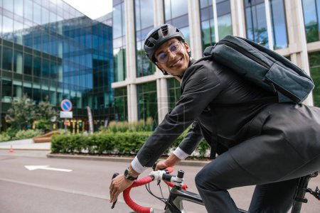 Téléchargez les photos : Au bureau. Jeune homme en vélo dans un centre-ville - en image libre de droit