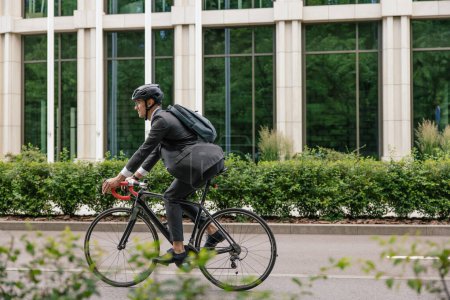 Foto de Así se hace. Hombre en dobladillo y con una mochila montando una bicicleta - Imagen libre de derechos