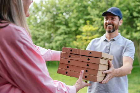 Photo for Smiling deliveryman handing grocery or pizza to woman home. - Royalty Free Image