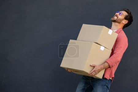 Téléchargez les photos : Un homme avec des boîtes. Satisfait jeune maman avec des boîtes en carton lourd dans les mains - en image libre de droit