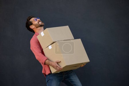 Photo for Man with boxes. Contented young ma with heavy carton boxes in hands - Royalty Free Image