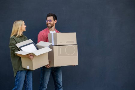 Photo for Move to new house. Young couple moving to a new house and carrying boxes with clothes - Royalty Free Image