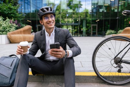 Photo for Mornig coffee. Man in hemlet having coffee after cycling to the office - Royalty Free Image