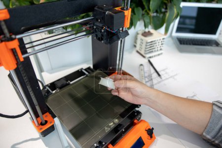 Téléchargez les photos : Gros plan de l'homme vérifiant l'imprimante 3D, processus de fabrication des choses sur imprimante 3D en laboratoire. - en image libre de droit