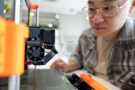 Téléchargez les photos : Asiatique homme vérification imprimante 3d, processus de fabrication des choses sur imprimante 3d en laboratoire. - en image libre de droit