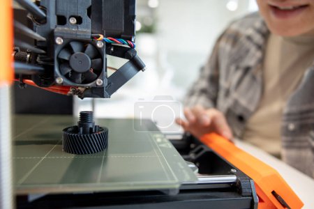 Foto de Primer plano de hombre que comprueba la impresora 3d, proceso de hacer cosas en la impresora 3d en el laboratorio. - Imagen libre de derechos