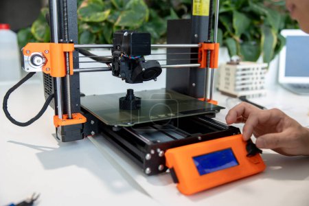 Closeup of man checking 3d printer, process of making things on 3d printer in laboratory.