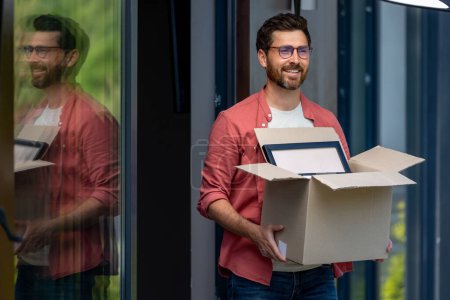 Photo for Relocation. Dark-haired bearded young man with box in hands - Royalty Free Image