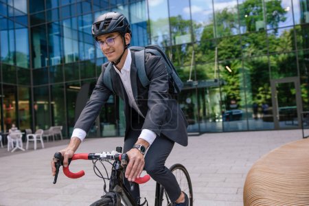 Téléchargez les photos : Transport écologique. Jeune manager se rendant au bureau à vélo - en image libre de droit