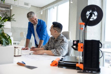 Photo for Experimental engineers men working with 3D printer and blueprint for designing mechanical parts in high tech workshop. - Royalty Free Image