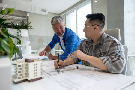 Téléchargez les photos : Équipe de deux architectes hommes utilisant une imprimante 3D dans un bureau et une maison en saillie, dessinant des plans. - en image libre de droit