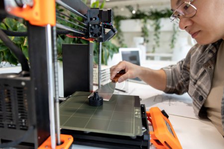 Foto de Ingeniero de diseño asiático usando impresora 3D en laboratorio y estudiando el prototipo de producto, la tecnología y el concepto de innovación. - Imagen libre de derechos