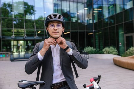 Téléchargez les photos : Un homme à vélo. Jeune homme d'affaires portant ourlet protecteur avant le vélo - en image libre de droit