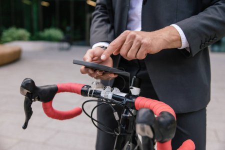 Téléchargez les photos : Louer un vélo. Homme utilisant l'application mobile et déverrouiller le parking - en image libre de droit