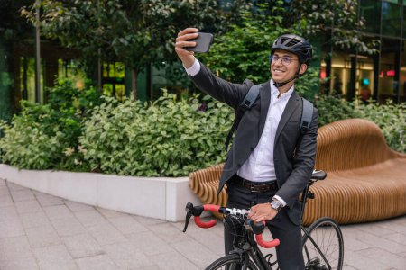 Foto de Selfie en scooter. Hombre de negocios sonriente en hemlet en una scooter haciendo selfie - Imagen libre de derechos