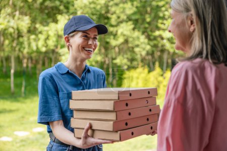 Téléchargez les photos : Livraison de nourriture. Courrier féminin livrant la pizza à la maison du client. - en image libre de droit