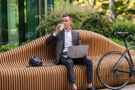 Photo for Business morning. Handsome young businessman working on laptop and drinking coffee - Royalty Free Image