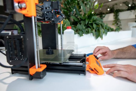Téléchargez les photos : Designer professionnel méconnaissable travaillant sur une imprimante 3D. - en image libre de droit