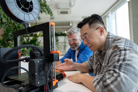 Foto de Colegas ingenieros que trabajan con el proceso de impresión de impresoras 3D. - Imagen libre de derechos