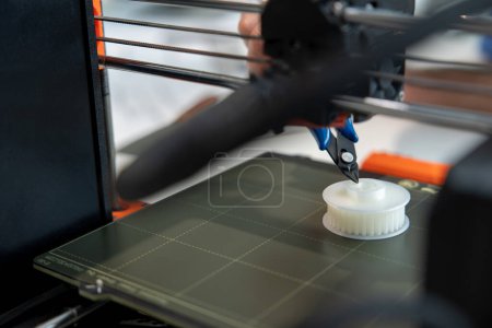 Téléchargez les photos : Designer méconnaissable travaillant avec l'imprimante 3D laboratoire créatif. - en image libre de droit