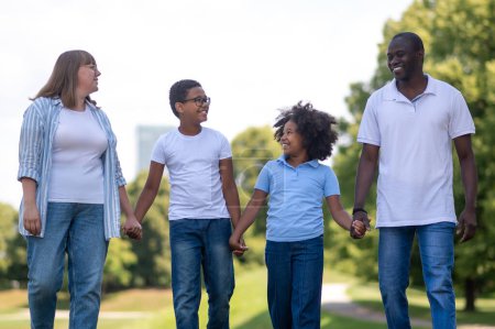 Téléchargez les photos : Du temps en famille. Famille Interraciale dans le parc ensemble regardant heureux - en image libre de droit