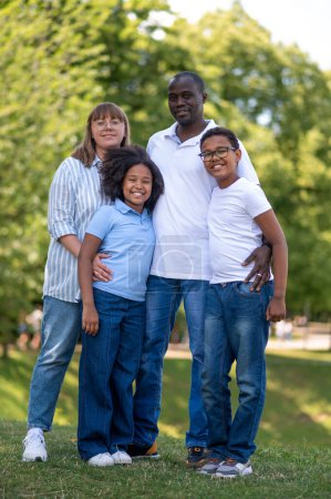 Téléchargez les photos : Du temps en famille. Famille Interraciale dans le parc ensemble regardant heureux - en image libre de droit