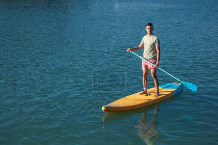 Foto de Hombre atlético a bordo flotando en el mar del océano. - Imagen libre de derechos