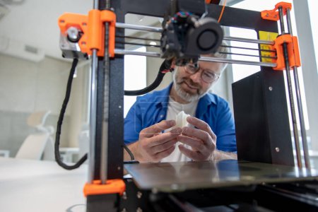 Foto de Diseño de impresión de hombre maduro con impresora 3D en la oficina. - Imagen libre de derechos