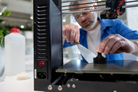 Foto de Diseño de impresión de hombre maduro con impresora 3D en la oficina. - Imagen libre de derechos
