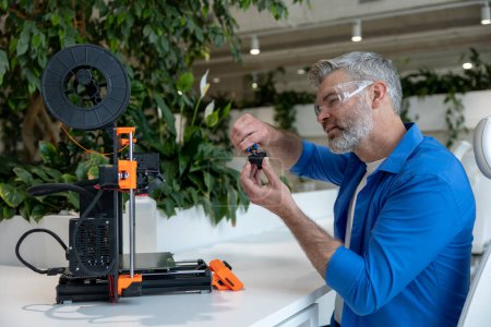 Photo for Modern 3D printer equipment and mature man working with it in office. - Royalty Free Image