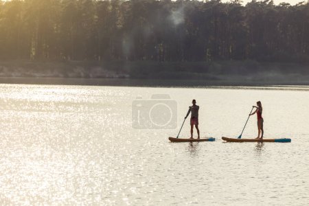 Foto de Feliz pareja hombre y mujer flota en el río en supboard, deporte de estilo de vida de verano por diversión. - Imagen libre de derechos
