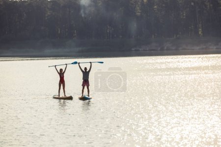 Téléchargez les photos : Happy couple homme et femme flotte sur la rivière sur le supboard, sport de style de vie d'été pour le plaisir. - en image libre de droit