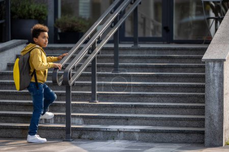 Photo for Boy on the stairs. African american schoolboy with a backpack on the stairs - Royalty Free Image