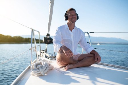Téléchargez les photos : Méditation sur un yacht. Homme assis dans une pose de lotus et méditant - en image libre de droit