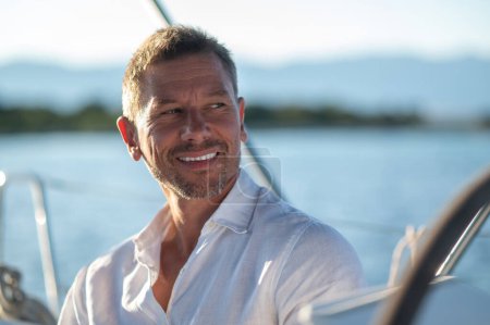 Téléchargez les photos : Un homme heureux. Homme souriant voyageant sur un yacht et regardant satisfait - en image libre de droit