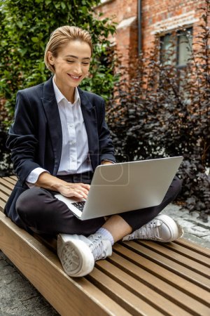 Photo for Work balance. Young business woman sitting in a lotus pose and working on laptop - Royalty Free Image