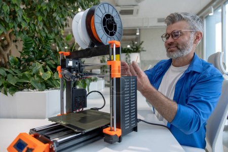 Photo for Mature man designer printing design using 3D printer in office. - Royalty Free Image