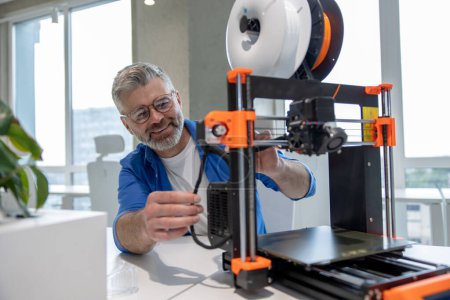 Photo for Mature man designer printing design using 3D printer in office. - Royalty Free Image