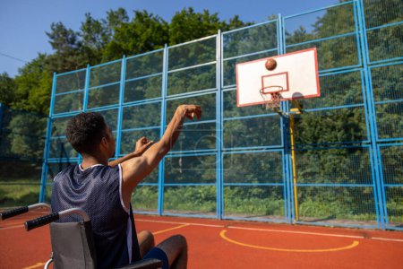 Téléchargez les photos : Homme noir sportif handicapé jouant au basket lançant la balle sur le terrain de jeu. - en image libre de droit