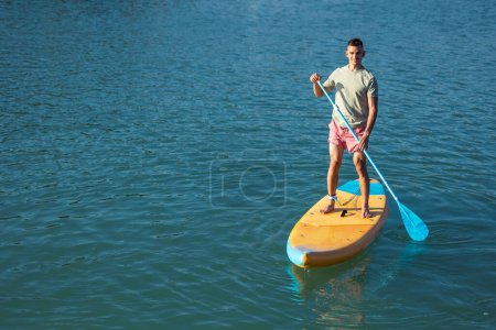 Téléchargez les photos : Beau homme debout sur le supboard dans l'océan. - en image libre de droit