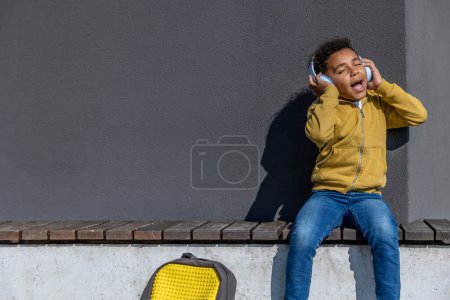 Photo for Listening to music. Cute schoolboy in headphones listening to music and looking enjoyed - Royalty Free Image