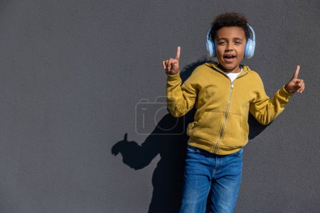 Photo for Leisure. Cute schoolboy in headphones listening to music and looking contented - Royalty Free Image