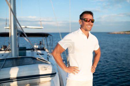 Téléchargez les photos : Bonne vie. handosme confiant homme en lunettes de soleil sur un yacht - en image libre de droit