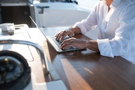 Photo for Digital nomad. Confident man in sunglasses working on a laptop while sailing on a yacht - Royalty Free Image