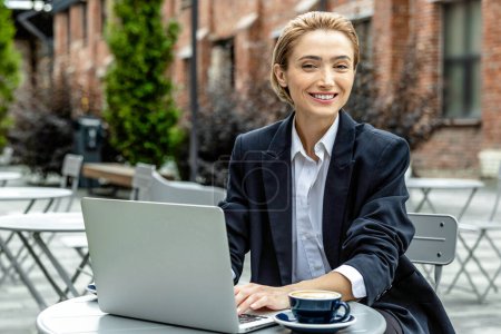 Foto de Mujer de negocios. Joven mujer de negocios bastante sentado en la cafetería y trabajando en el ordenador portátil - Imagen libre de derechos