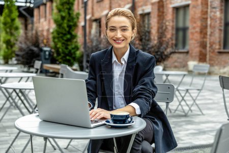 Foto de Mujer de negocios. Joven mujer de negocios bastante sentado en la cafetería y trabajando en el ordenador portátil - Imagen libre de derechos