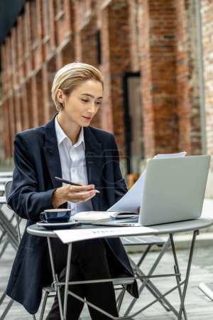 Foto de Nómada digital. Mujer de negocios sentada a la mesa en un café de la calle y trabajando - Imagen libre de derechos